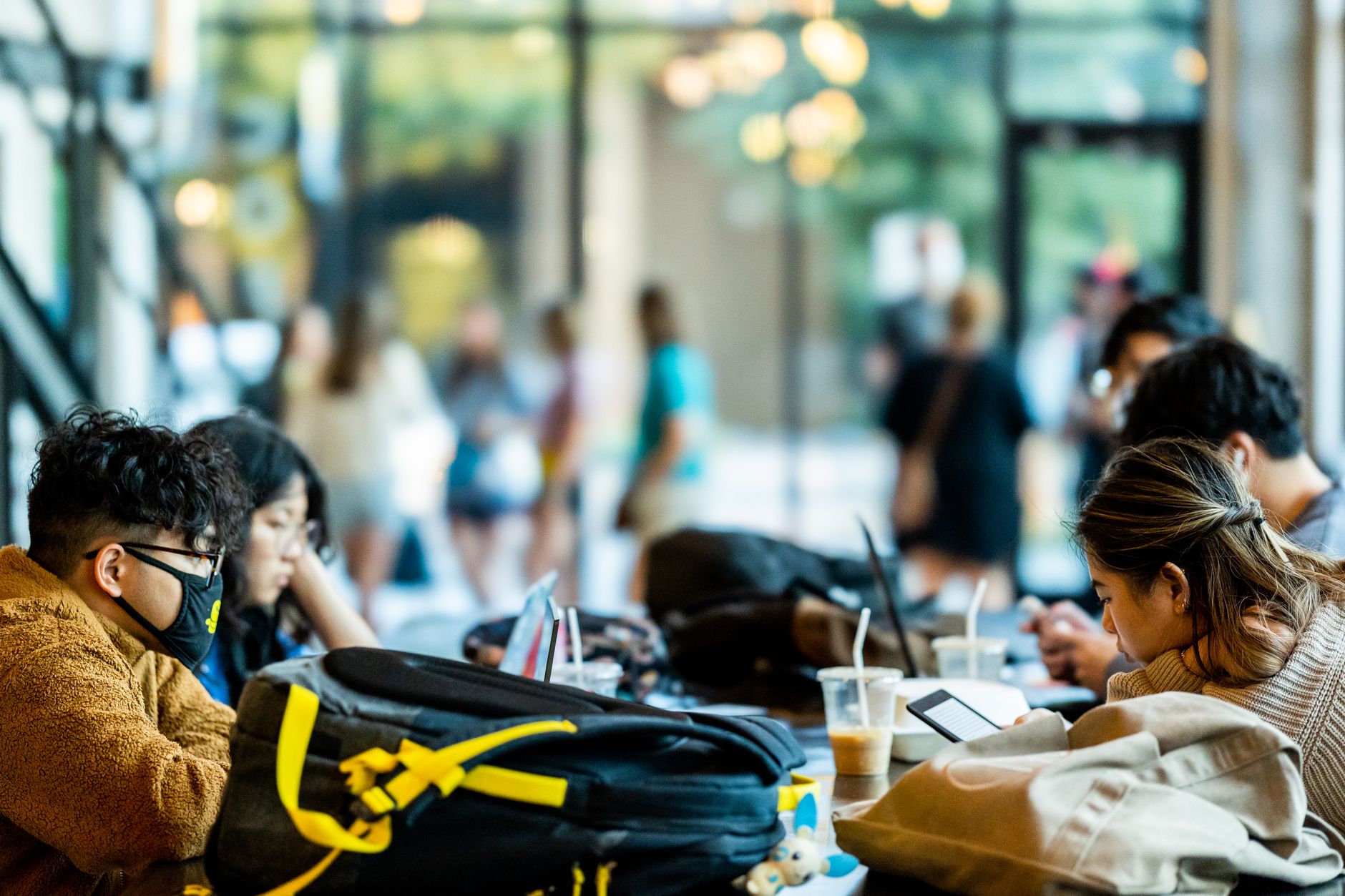 leaseradius-1786890844488 Students focused on their studies in a bustling university lounge with laptops and coffee.