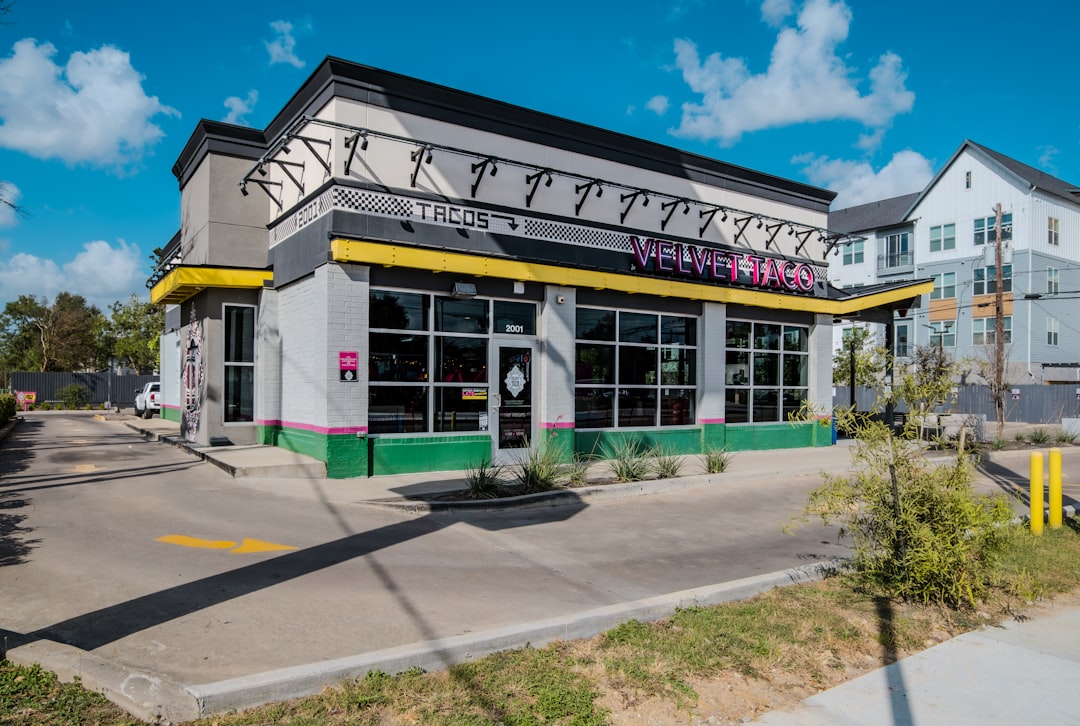 Tree-lined street in Montrose Houston with outdoor cafe seating on a sunny morning
