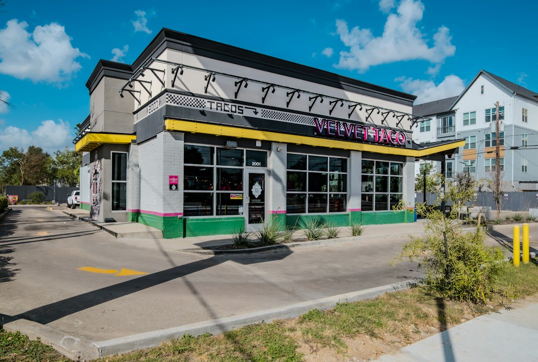 Tree-lined street in Montrose Houston with outdoor cafe seating on a sunny morning